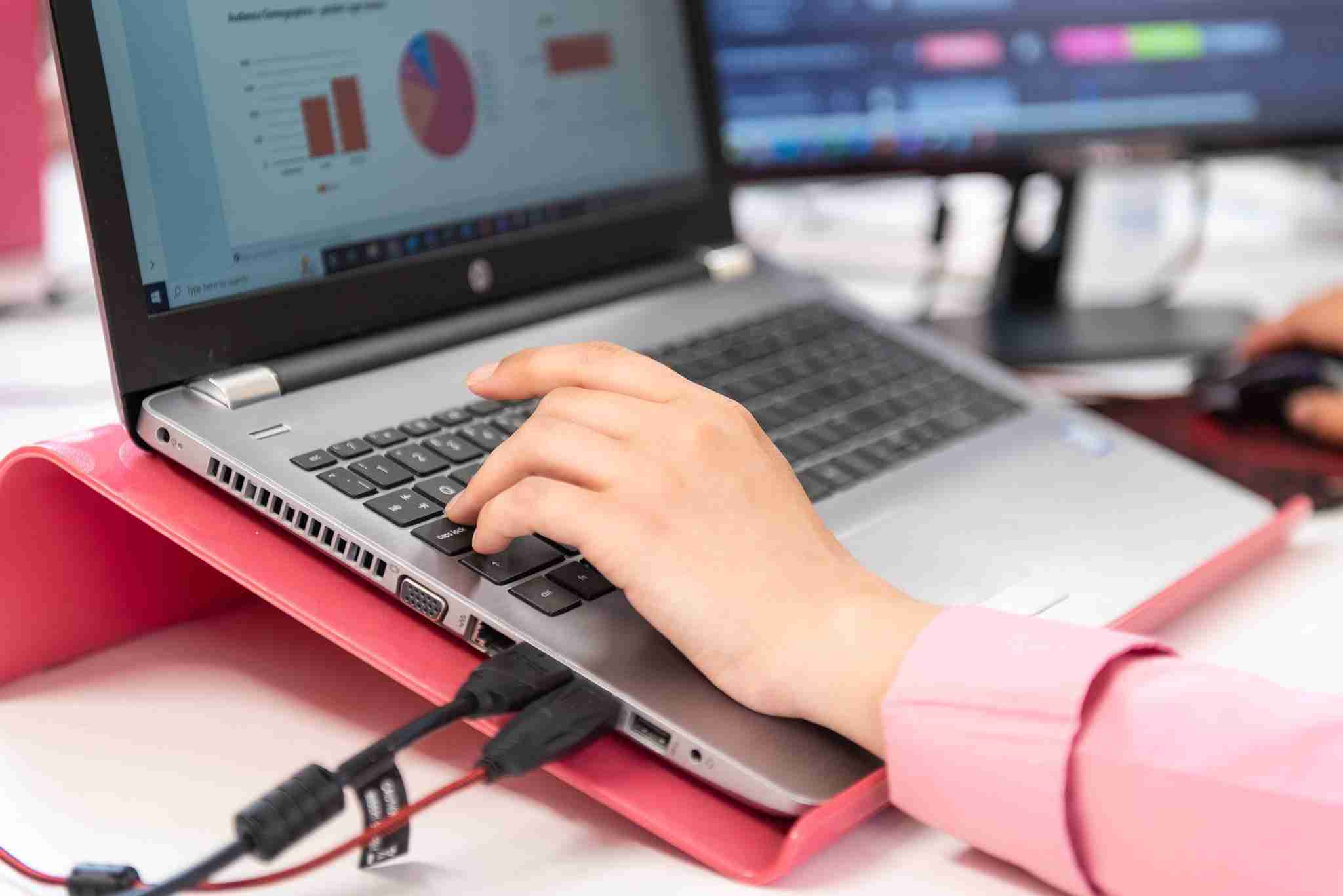 Automation Digital marketer's hand at a laptop as they prepare a set of email automations